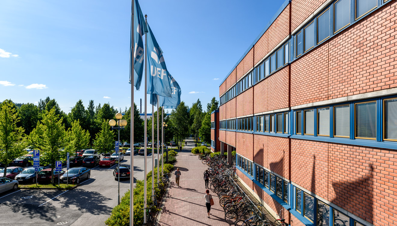 UEF Canthian rakennus ulkoapäin. Oikealla on Canthian punatiilinen rakennus ja vasemmalla parkkipaikka. The UEF Canthia building from the outside. On the right is the red-brick Canthia building, and on the left is the parking lot.