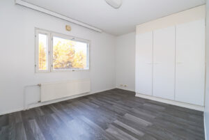 Haapaniementie 24 asunnon makuuhuone, jossa on paljon kaappitilaa. Lattiat ovat puunsävyistä laminaattia. Haapaniementie 24 apartment's bedroom with plenty of closet space. The floors are wood-colored laminate.