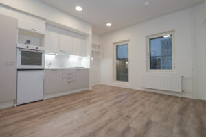 Kuopas Kampus Ankkurin asunto, jossa on keittiössä vaaleat pinnat. Keittiön vieressä on opiskelutila ja hylly seinällä. Asunnossa on ranskalainen parveke. Lattiat ovat vaaleaa laminaattia. Kuopas Kampus Ankkuri apartment with light-colored surfaces in the kitchen. Next to the kitchen is a study area and a shelf on the wall. The apartment has a French balcony. The floors are light-colored laminate.