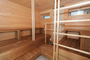 Kuopas Kampus Ankkurin sauna. Molemmin puolin kiuasta on lauteet ja saunaan on tehty kaiteet ohuella rimoituksella. Kuopas Kampus Ankkuri sauna. There are benches on both sides of the sauna stove, and the sauna has been fitted with thin railings.