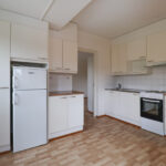 Kuopas Neulamäentie 3 asunnon vaalea keittiö, jossa on paljon kaappitilaa. Lattiat ovat puunväriset. The light-colored kitchen of the Kuopas Neulamäentie 3 apartment has plenty of cabinet space. The floors are wood-colored.