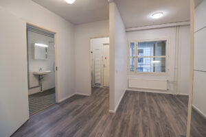 Rimpitie 1 asunto kuvattuna eteiseen päin. Asunnossa on tummat laminaattilattiat ja remontoitu kylpyhuone. Rimpitie 1 apartment photographed facing the hallway. The apartment has dark laminate flooring and a renovated bathroom.