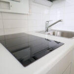 Keittiön työtaso, allas ja liesitaso uudessa Savilahden opiskelija-asunnossa. Kitchen countertop, sink and stovetop in a new student apartment in Savilahti.
